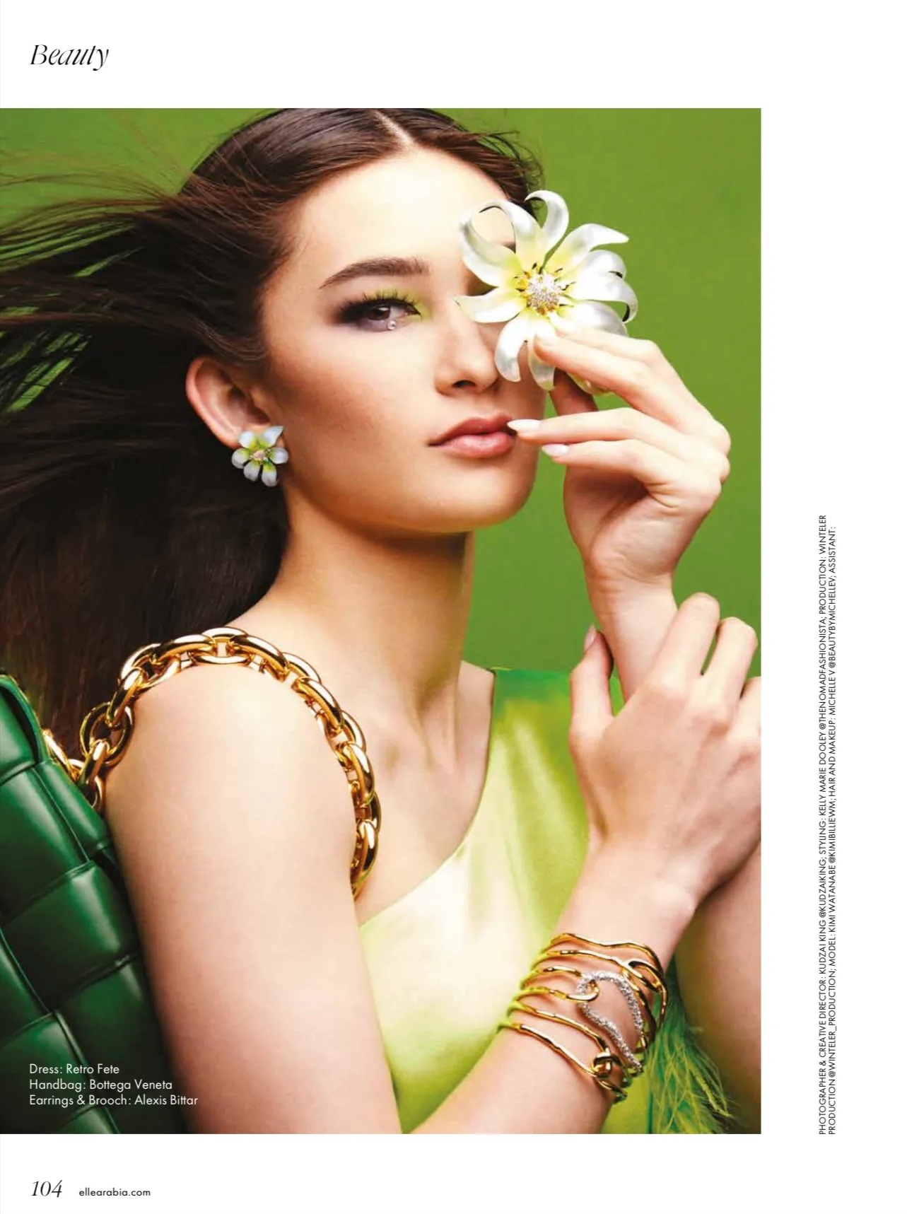 ELLE Arabia beauty page 104 showing a model holding a white flower against a green background, with printed credits.