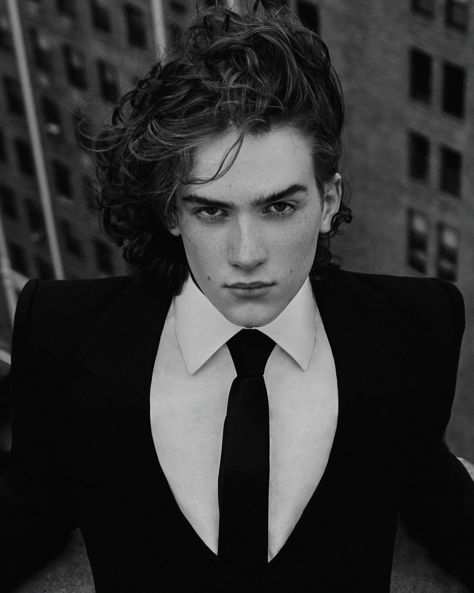 Black-and-white rooftop portrait of a model in a shirt and tie.