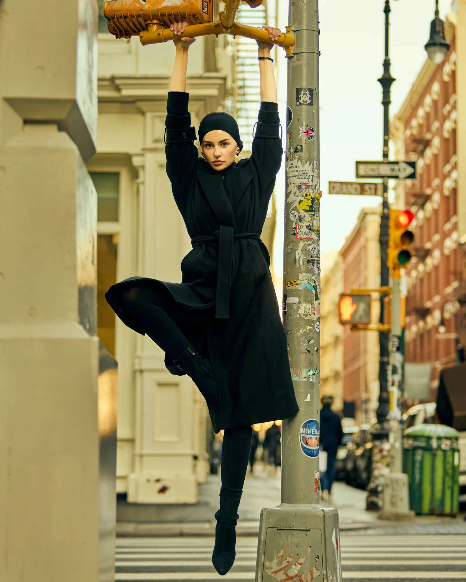 A model in black tailoring suspended from a street pole.