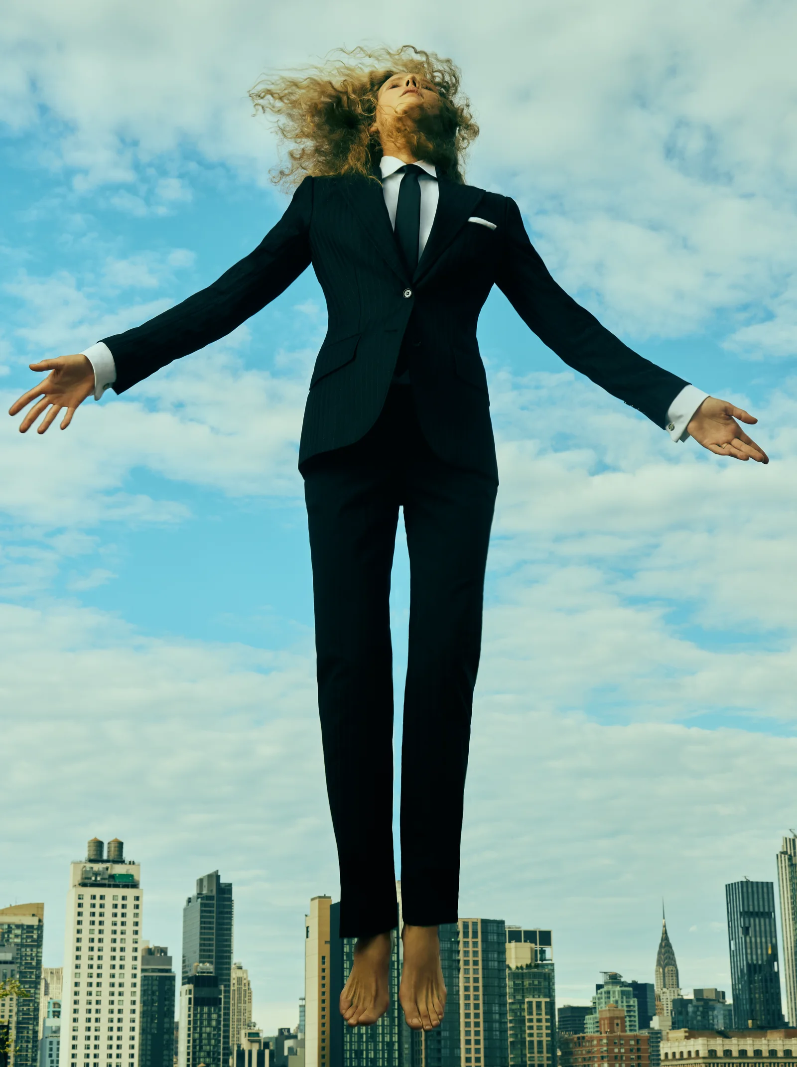 A model in black tailoring jumping above the New York skyline. The Modern Armor.