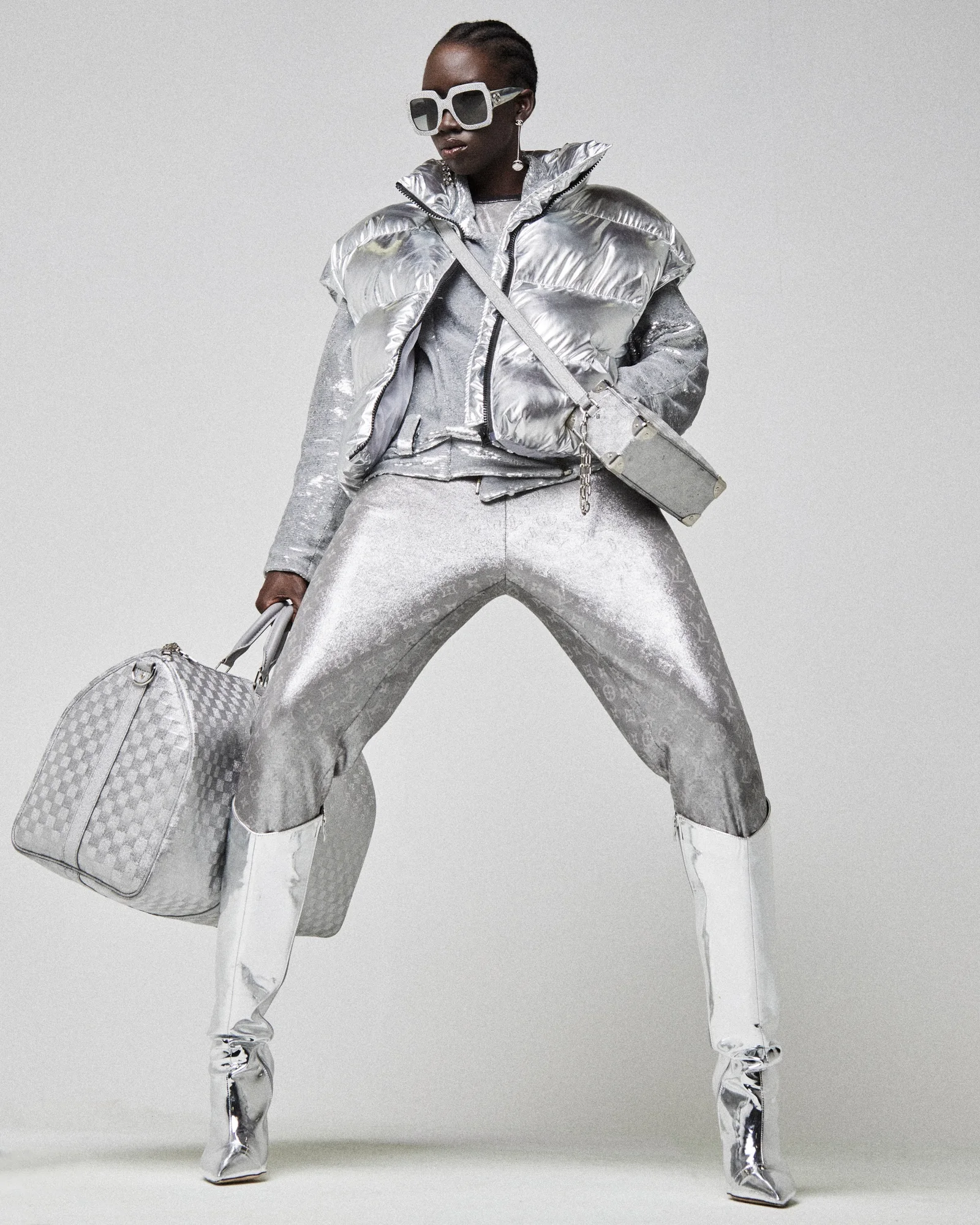 A model in silver metallic styling, white boots and white sunglasses.