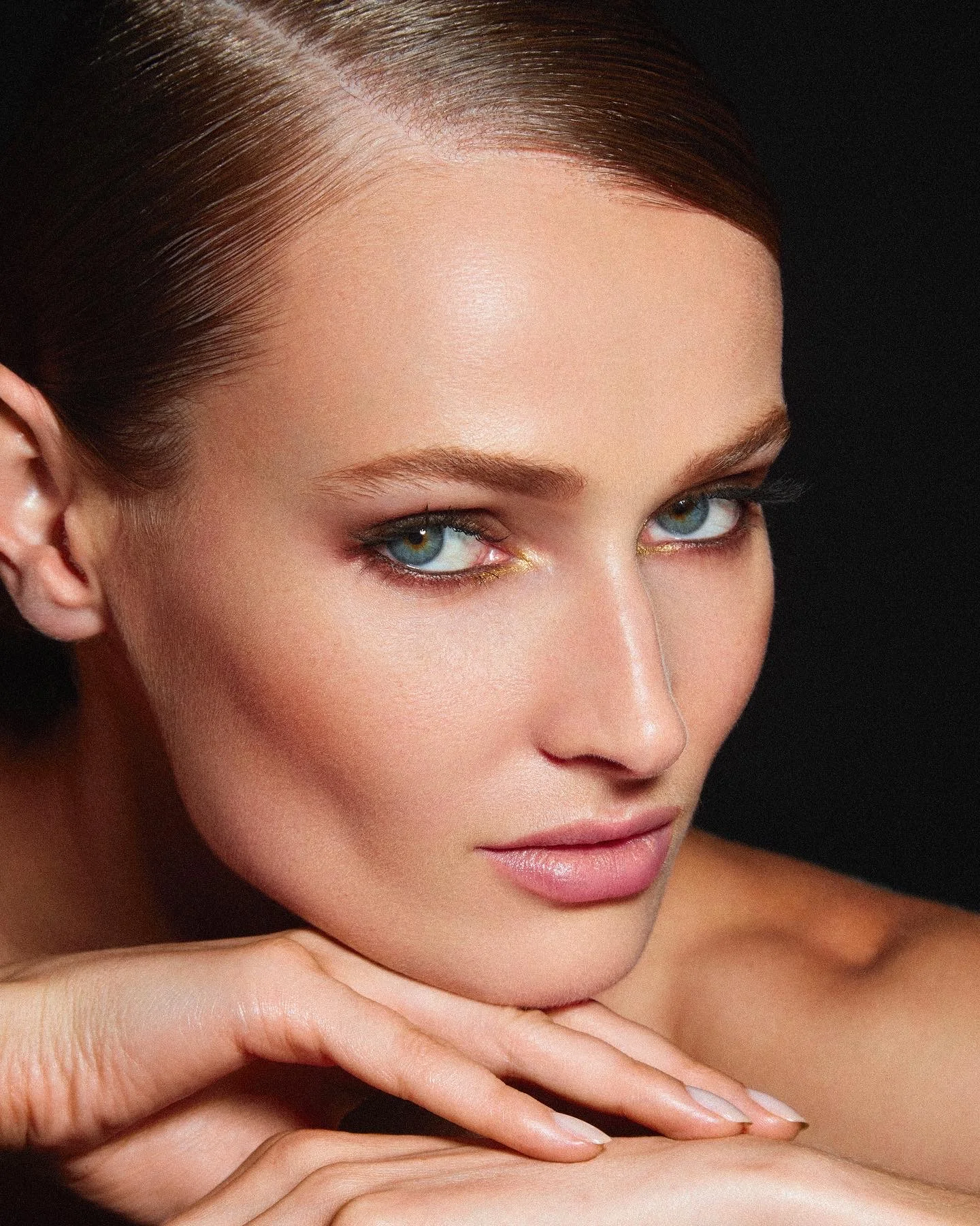 A close beauty portrait of a model resting her chin on her hand.
