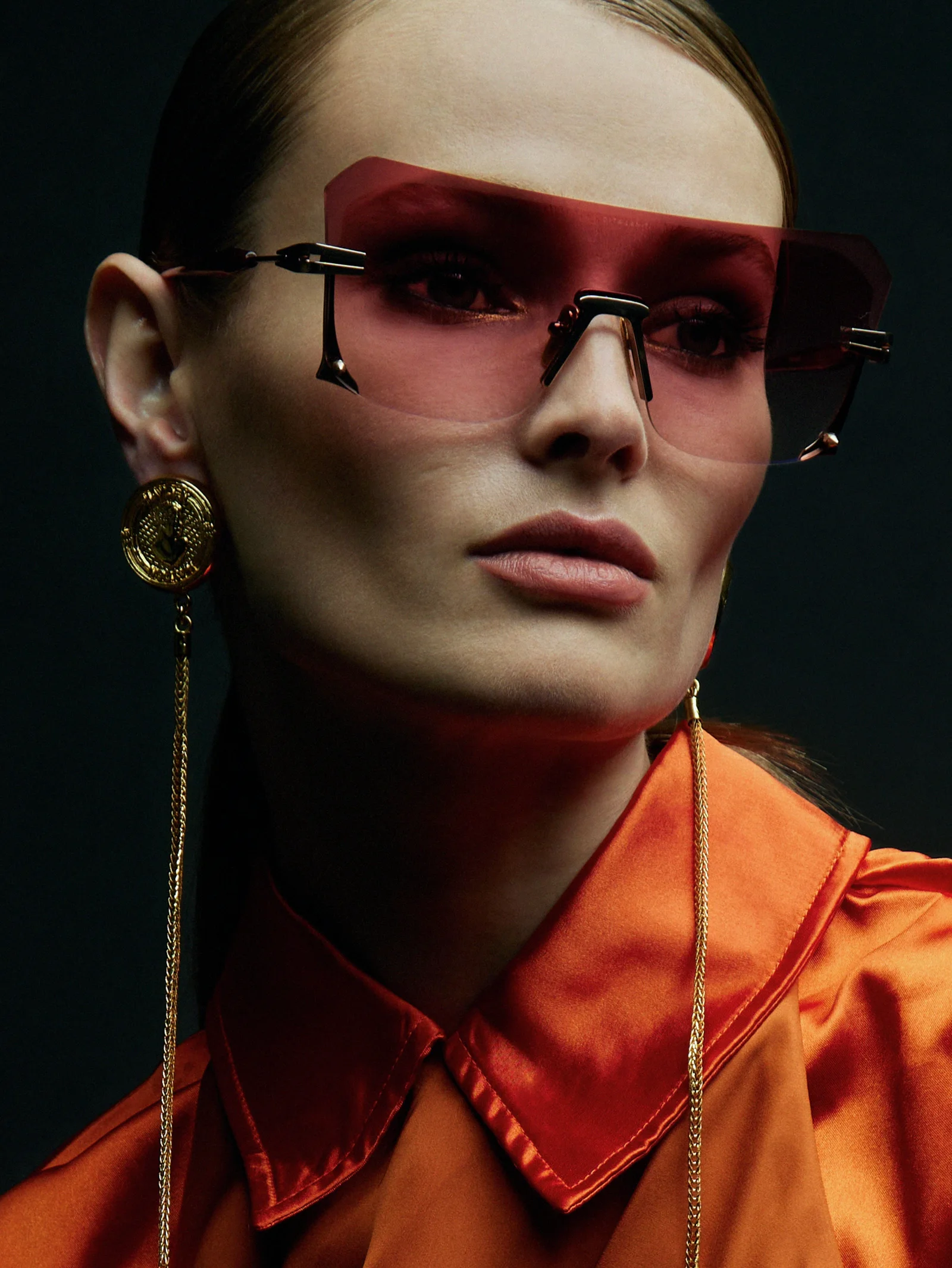 A close eyewear portrait in red sunglasses and an orange shirt.