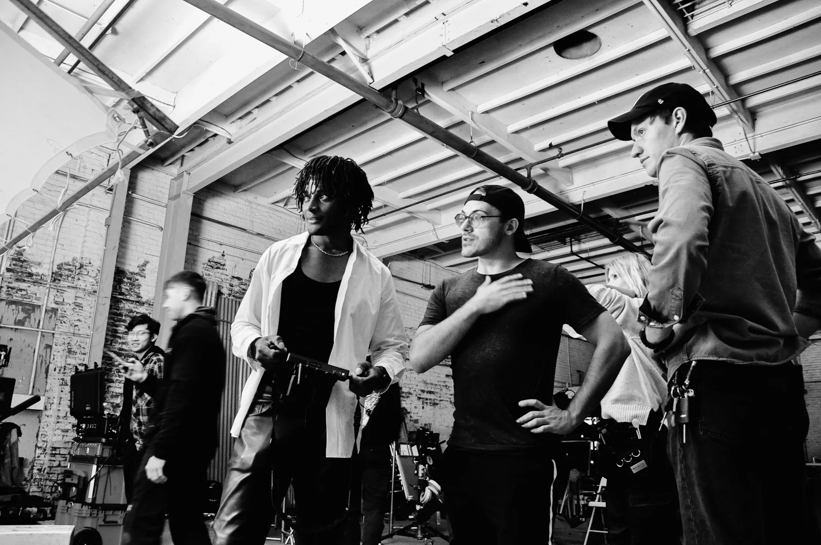 Black-and-white image of Kudzai King and crew beside production equipment in a daylight studio.